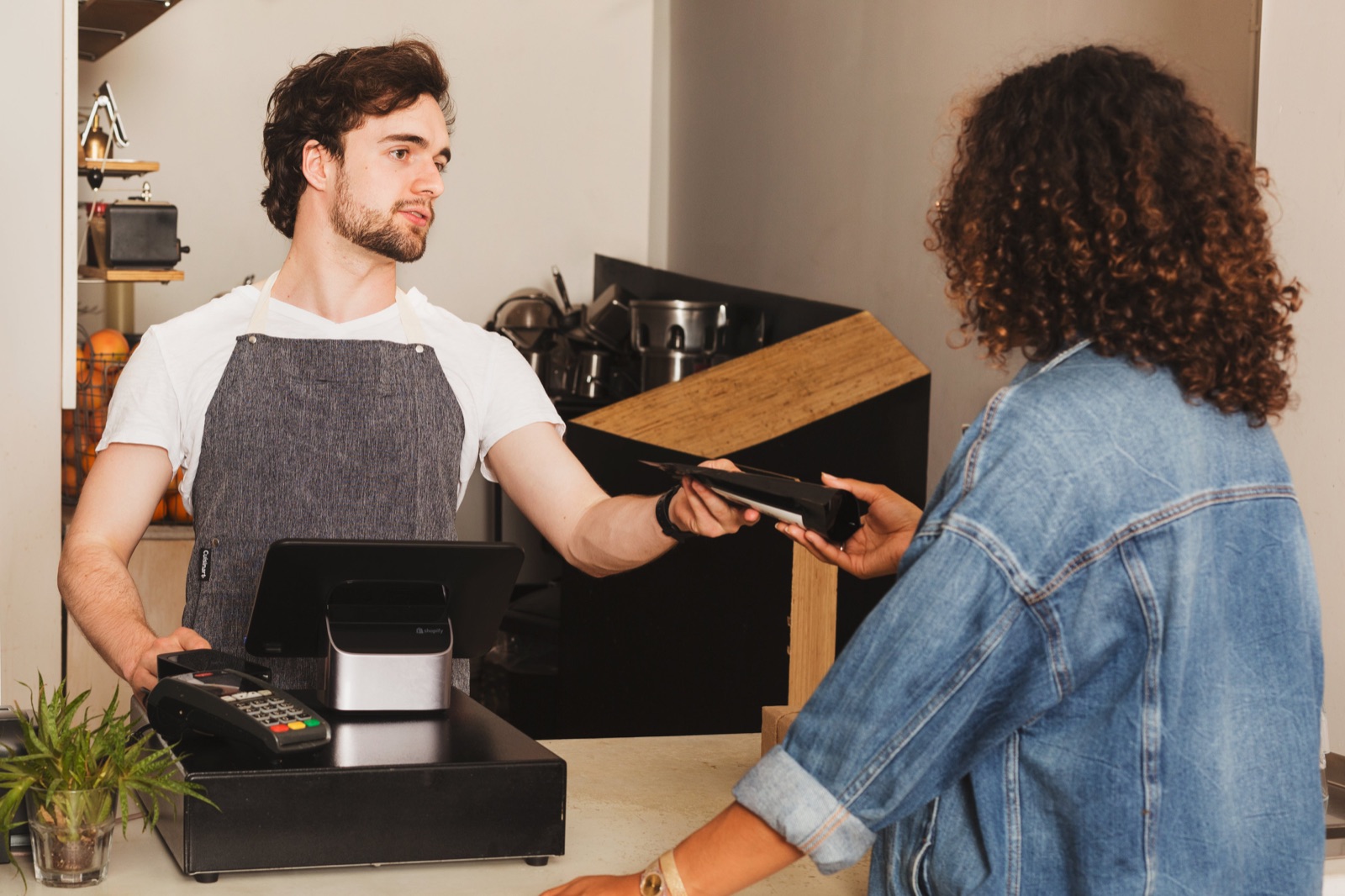 Customer tapping a card to pay at a caf&eacute; counter