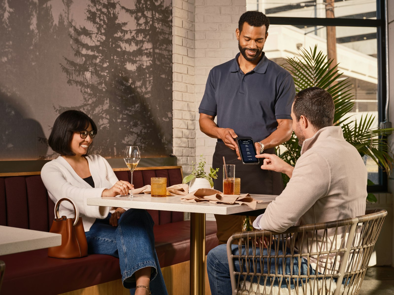 Waiter taking an order on a handheld POS at a restaurant table